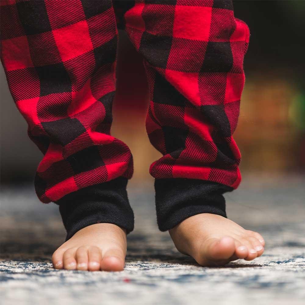 Ett par barnfötter går barnfota på en mysig matta utan strumpor.