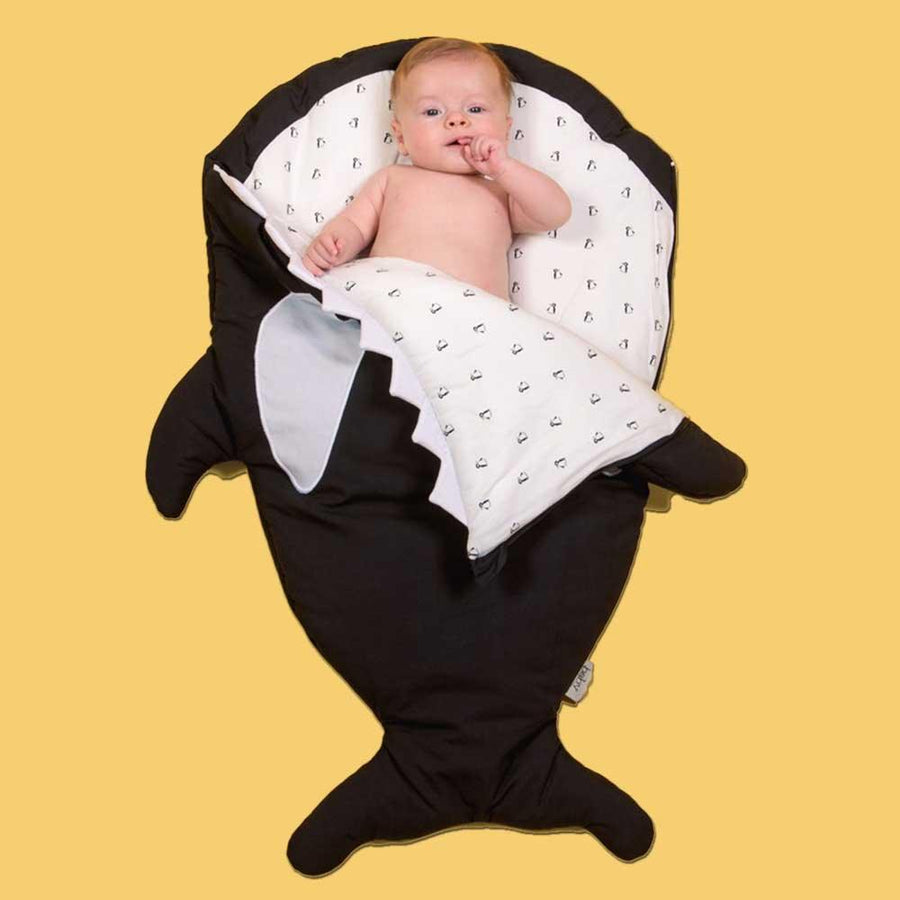 En bebis som ligger i en sovpåse formad som en haj från märket Baby Bites och Maggie Mars.