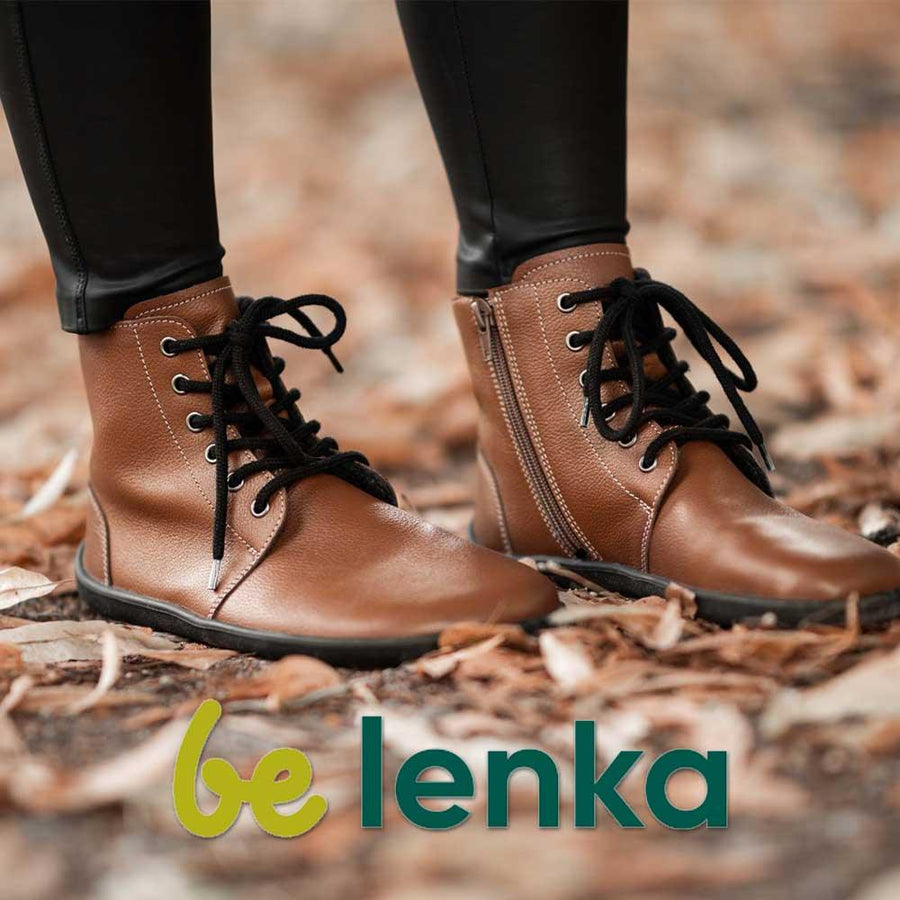 En vuxen kvinna står på höstlöv i ett par barfotaskor från varumärket Be Lenka. Hennes fötter är inzoomade.