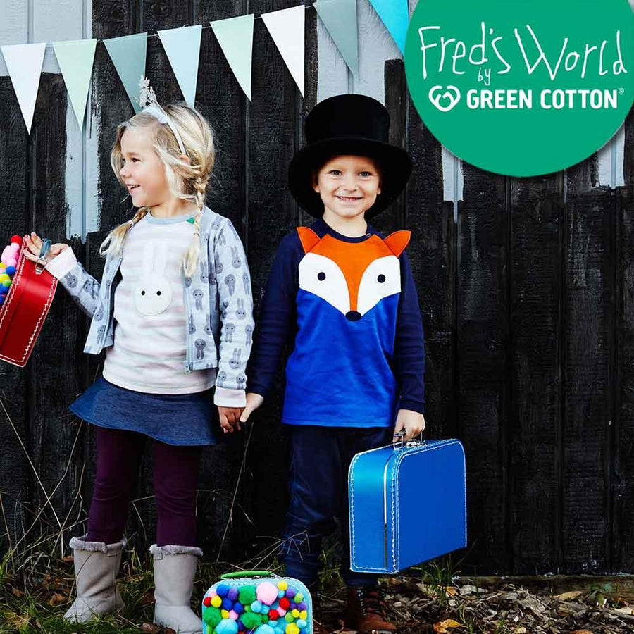 En pojke och en flicka står utomhus klädda i Fred's World Green Cotton och bär på väskor.
