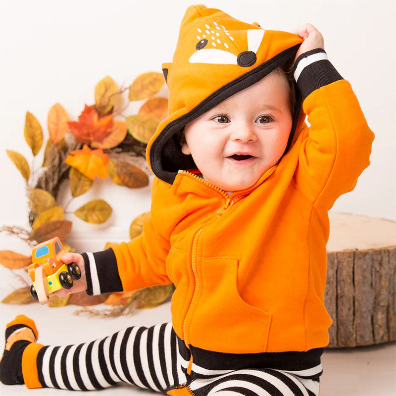 Ett barn sitter och leker i en orange hoodie barnkläder från Blade & Rose.